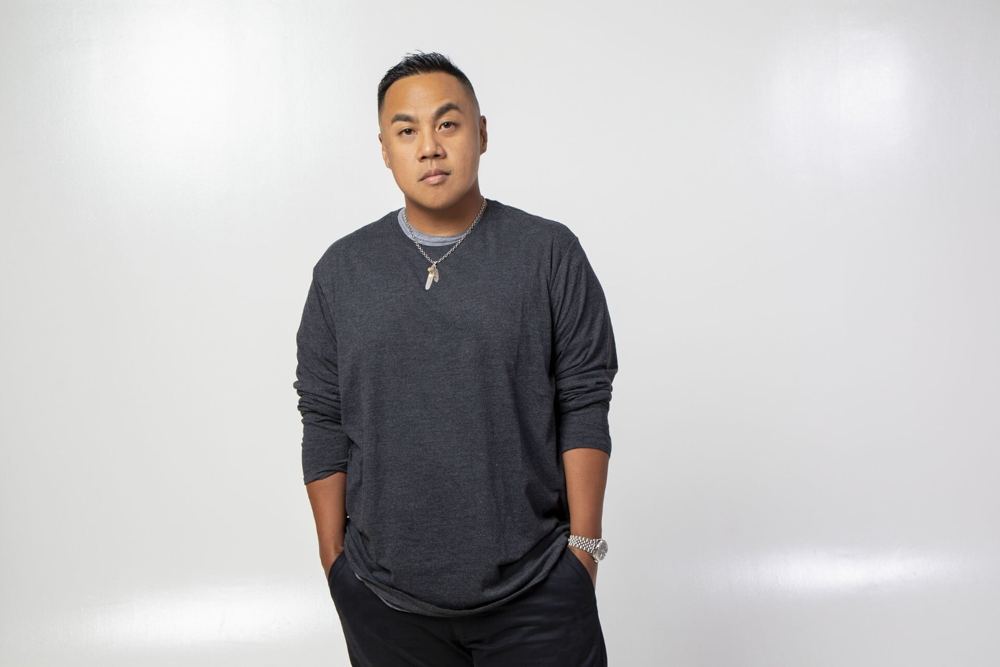 DJ Compose in a grey sweater against a white backdrop.