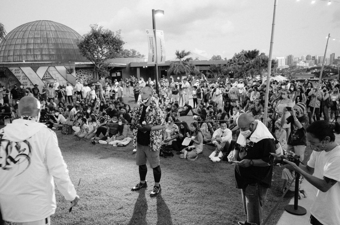A large crowd on the museum lawn in front of the planetarium dome watching artists perform.